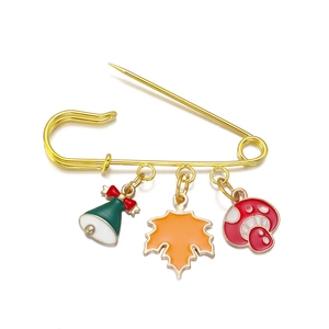 Gold safety pin brooch with Christmas bell, maple leaf and red mushroom charms