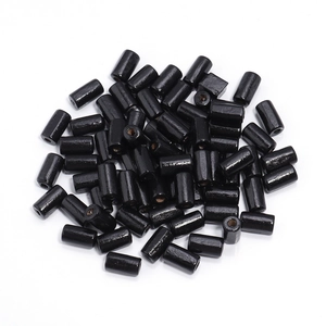 Close-up of polished black cylindrical maple wood beads with center holes for DIY crafting
