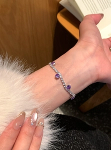 Detail eines funkelnden Silberarmbands mit runden lila und klaren Zirkonia-Steinen.