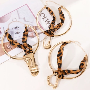 Detail view of leopard print ribbon neck collars with gold abstract face pendants