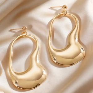 Macro view of gold liquid-style irregular hollow earrings on silk