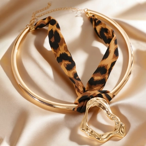 Macro view of chunky gold liquid metal choker necklace featuring leopard print silk ribbon