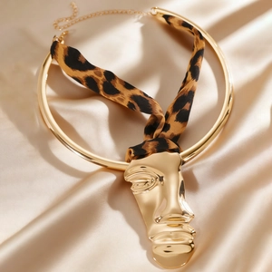 Close-up of golden abstract face pendant and leopard print ribbon choker necklace