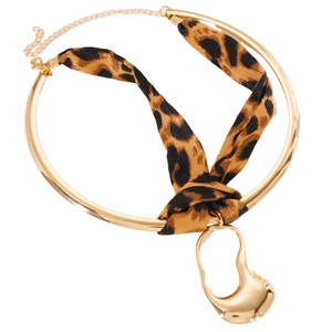 Macro detail of a leopard print ribbon choker featuring a gold irregular liquid metal charm