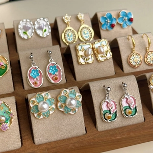 Detailed macro view of various Monet Garden style enamel flower and pearl drop earrings