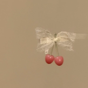 Close-up of a sweet lace bow hair clip featuring two cute pink cherry pendants on a beige background