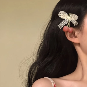Close-up of sweet lace bow hair clip with cherry pendants on dark wavy hair.