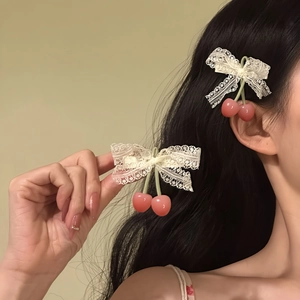 Detailed view of a sweet white lace bow hair clip featuring cute pink cherry pendants