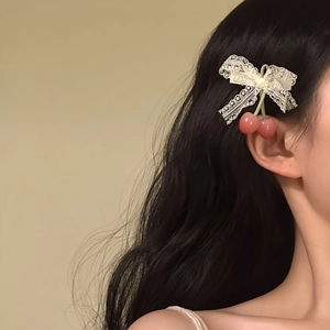 Close-up of sweet lace bow hair clip with pink cherry pendants on wavy black hair.