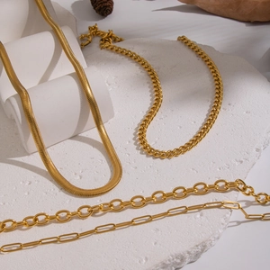 Four styles of 18K gold plated stainless steel necklaces on a white stone texture.