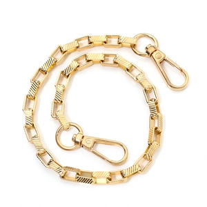 Macro detail of golden square link chain with diagonal texture and lobster clasps