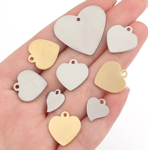 Polished heart-shaped stainless steel charms in various sizes held in hand for scale
