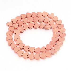 Close-up of heart-shaped rose gold hematite beads arranged in a double circle for DIY jewelry