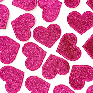 Detailed close-up of pink glitter heart embroidery patches with sparkling texture