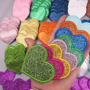 Detailed close-up of colorful glittery heart embroidery patches for DIY clothing