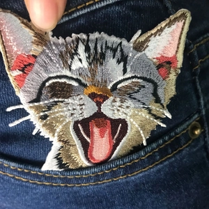 Detailed cat embroidery patch on denim pocket showing fine stitching and vivid feline texture