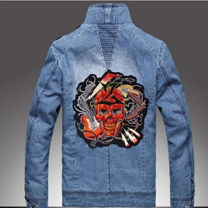 Detail of hard rock embroidered patch on back of blue denim jacket with skull and guitars