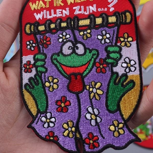 Détail d'écusson brodé grenouille avec fleurs colorées et décoration de texte néerlandais