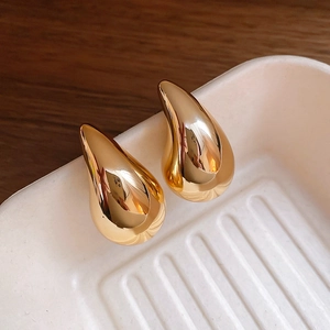 Detailaufnahme von hochglänzenden goldenen Tropfenohrringen mit minimalistischem Design
