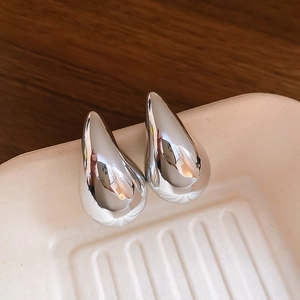 Macro-weergave van minimalistische zilveren druppelvormige oorknopjes gepolijst