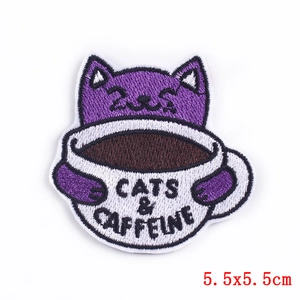Detailed close-up of a purple cat patch with Cats & Caffeine embroidery on white background