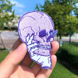 Punk purple skull clown embroidery patch with hand holding in outdoor nature setting