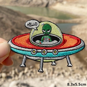 Macro detail of UFO and green alien embroidery patch with Hello text and vivid colors