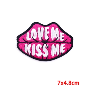 Embroidered lip patch in magenta and black featuring LOVE ME KISS ME text, 7x4.8cm size