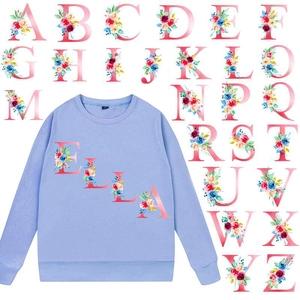 Vue détaillée de patchs thermocollants à lettres florales sur un sweat-shirt bleu clair