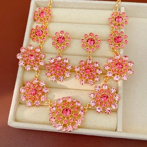 Primer plano de collar y pendientes vintage dorados con piedras de cristal rosa
