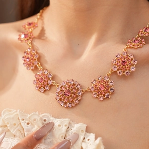 Primer plano de un collar vintage circular con pedrería rosa brillante en la piel.