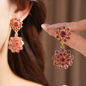 Primer plano detallado de pendientes vintage dorados con cristales morados y rosas
