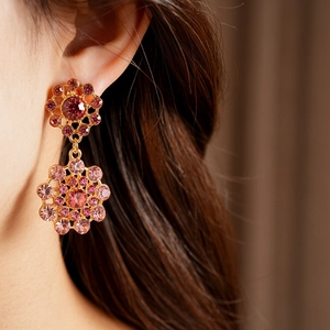 Primer plano detallado de pendientes vintage dorados con un diseño floral de cristal rosa