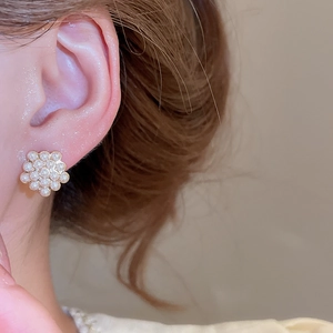 Macro view of an elegant flower-shaped pearl stud earring elegantly worn on model's ear