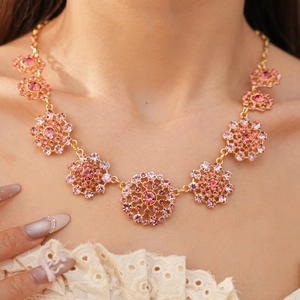 Primer plano de collar vintage dorado con colgantes florales de pedrería rosa