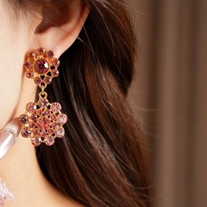 Primer plano de pendientes vintage elegantes con diamantes rosas y montura dorada.
