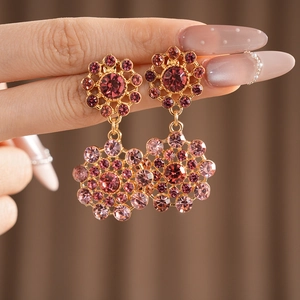 Detalle de pendientes vintage con piedras rosas brillantes y un elegante acabado dorado