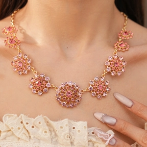 Primer plano de un collar de oro vintage con colgantes circulares de cristal rosa