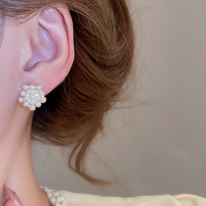 Elegant gold cluster pearl flower stud earrings shown as worn on a female ear model