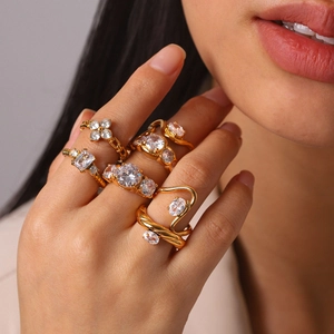 Detailed shot of several gold stainless steel rings with zircon stones on a female hand.