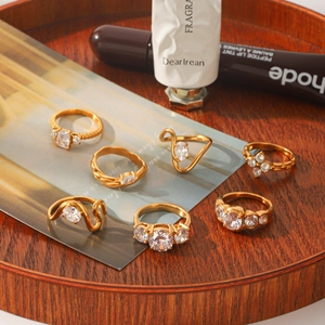 Close-up of elegant gold stainless steel rings with cubic zirconia on a rustic wooden tray