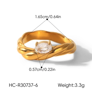 Detailed close-up of a gold-plated twisted titanium steel ring with an oval zircon