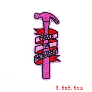 Détail d'écusson brodé Smash the Patriarchy avec motif marteau et ruban rouge