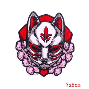 Close-up of Japanese kitsune fox mask embroidered patch with cherry blossom detail