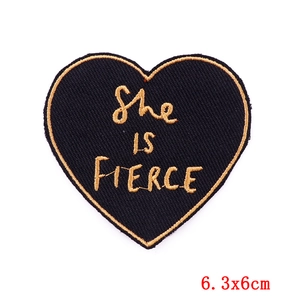Détail macro de l'écusson brodé cœur She Is Fierce avec bordure dorée, 6,3x6cm