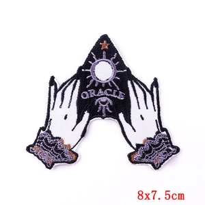 Close-up of embroidered ORACLE patch with mystic sun and star patterns in black and lilac