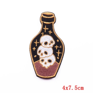 Detailed embroidery texture of a skull bottle patch measuring 4x7.5cm with gold stars