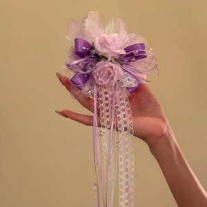 Hand-held view of an atmospheric purple lace flower hair clip with pink roses and ribbons.