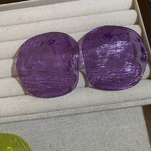 Deep purple irregular round resin stud earrings with a textured surface on a display tray
