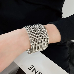 Dettaglio ravvicinato di un bracciale a più strati con perline argentate sul polso